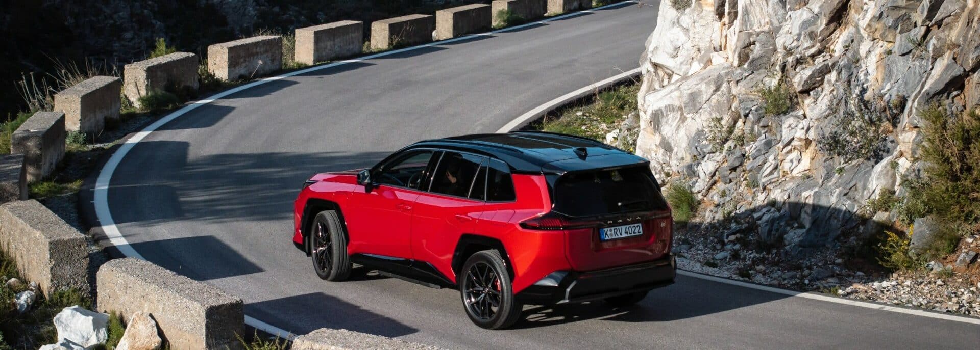 Raudonas Toyota RAV4 hibridas kalnų kelyje